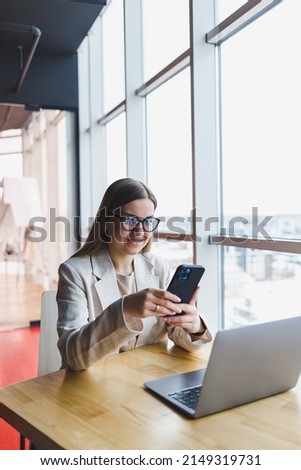 Young beautiful woman businessman uses smartphone for business, online shopping, money transfer, finance, internet banking. Woman working in a cafe Royalty-Free Stock Photo #2149319731