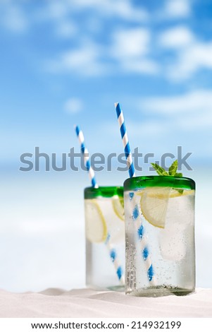 mojito cocktail with ice, rum, lemon and mint   in a  glass  on beach sand and seascape