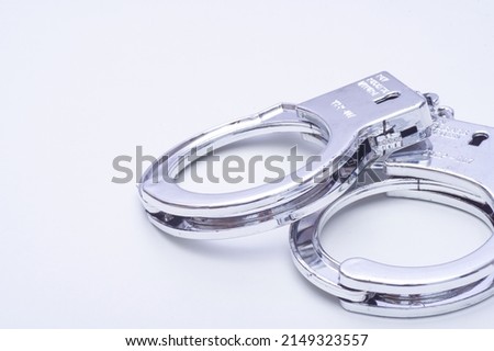 Handcuffs placed on a white table Royalty-Free Stock Photo #2149323557