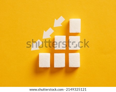 Ascending sugar cube graph with descending arrows indicating to reduce sugar intake and healthy nutrition. Royalty-Free Stock Photo #2149325121