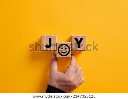 Hand places the word joy on wooden blocks with a smiling face symbol. Joy, happiness, pleasure, joyful emotion. Royalty-Free Stock Photo #2149325125