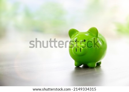 Green piggy bank on floor concept for saving, accounting, banking and business account or sustainable and environmentally friendly finance Royalty-Free Stock Photo #2149334315