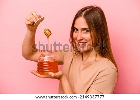 Young caucasian woman holding honey isolated on pink background Royalty-Free Stock Photo #2149337777