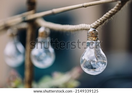 Decorative bulbs hanging on a rope. Outdoor creative decoration. Bokeh low aperture open diaphragm photography. Royalty-Free Stock Photo #2149339125