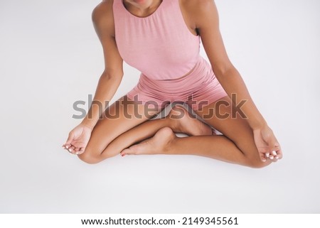 Cropped view of sportive fit girl dressed in pink tracksuit recreating during yoga session in white gym studio, unrecognizable woman in active wear enjoying leisure time for asana meditation