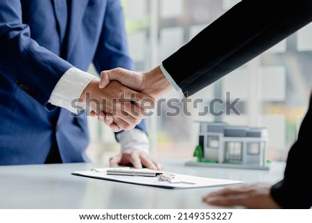 The salesperson of the housing estate in the project and the customer shake hands after successfully signing the contract. Concept of selling housing estates and real estate.