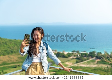 Young Asian woman traveler using mobile phone taking selfie while solo travel on tropical island mountain in summer sunny day. Attractive girl enjoy outdoor lifestyle in holiday beach vacation trip Royalty-Free Stock Photo #2149358581