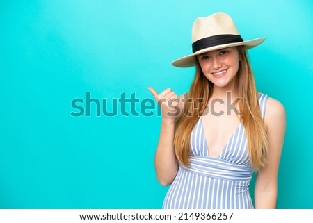 Young woman isolated on blue background in swimsuit and pointing side
