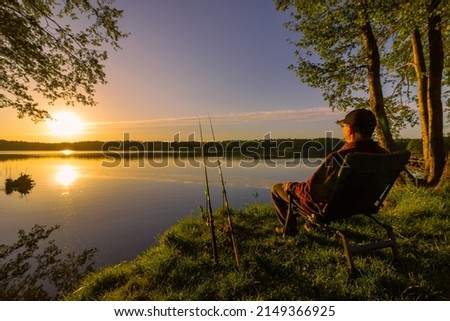 Angler sitting on fishing chair during sunrise Royalty-Free Stock Photo #2149366925