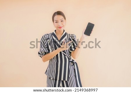 Portrait beautiful young asian woman with smart mobile phone on brown background