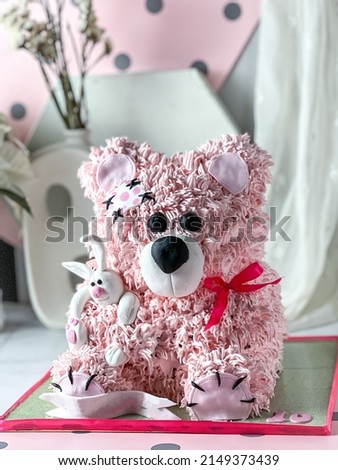 Teddy bear pink cake with buttercream against a white and pink background . The background is blurred and the image contains high luminance