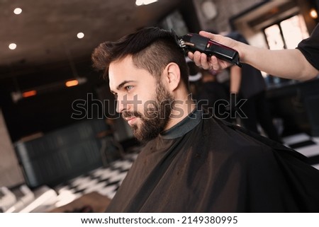 Professional hairdresser working with client in barbershop Royalty-Free Stock Photo #2149380995