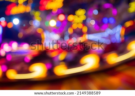 Unfocused lights of a Merry-go-round or carousel with colorful blue, red, yellow, pink and orange illumination. Blurred lights traces and spots taken with Long Time Exposure on a fun fair in Germany.  Royalty-Free Stock Photo #2149388589