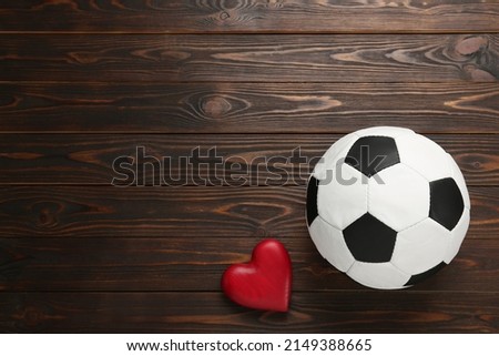 Soccer ball and heart on wooden background, flat lay. Space for text