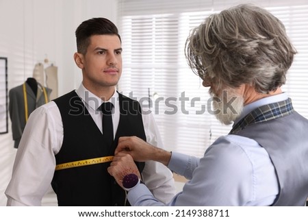 Professional tailor measuring client's chest circumference in atelier Royalty-Free Stock Photo #2149388711