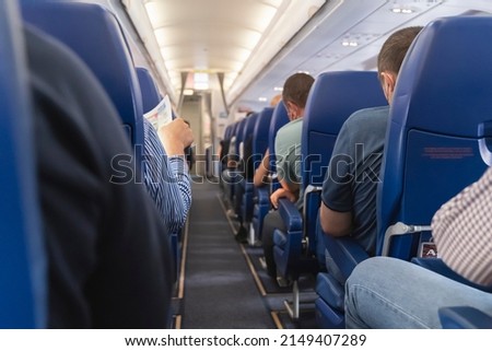 Passage in the plane.Economy class interior, aircraft cabin. Passengers sit in their seats.Family enjoying trip in aircraft. Transportation safety.  Royalty-Free Stock Photo #2149407289