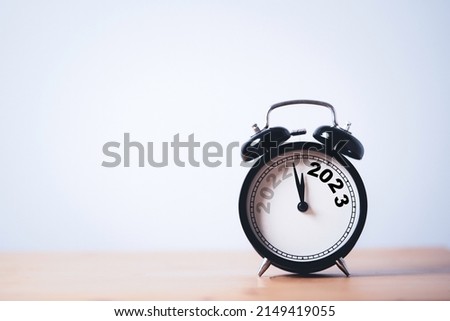 2022 year move to 2023 year on black alarm clock on wooden table with copy space for preparation Merry Christmas and Happy new year concept. Royalty-Free Stock Photo #2149419055