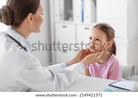 medicine, healthcare and pediatry concept - female doctor or pediatrician checking little girl patient's tonsils on medical exam at clinic Royalty-Free Stock Photo #2149421571