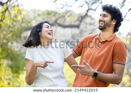 Happy young indian couple laughing in the summer park, cheerful urban man and woman wearing casual t-shirt having fun together, Stress free, Laughing therapy, Mental health. Good life. Relationship Royalty-Free Stock Photo #2149422019