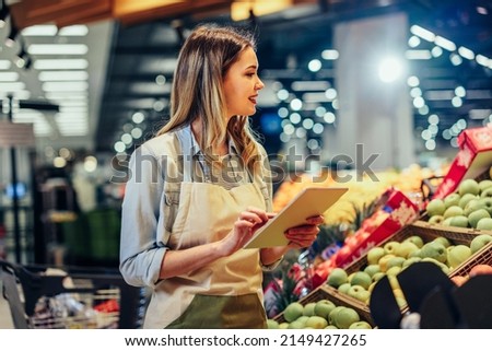 Woman working at a grocery store doing the inventory - small business concepts Royalty-Free Stock Photo #2149427265