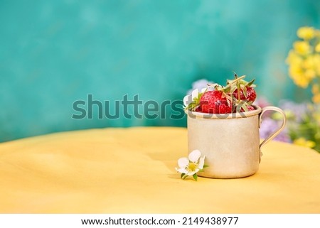 Strawberries in a metal aluminum travel mug, green and yellow background. Cottagecore aesthetics concept, trendy shadows background. Copy space. High quality photo