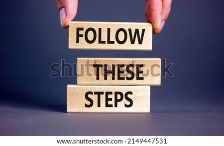 Follow these steps symbol. Concept words Follow these steps on wooden blocks. Businessman hand. Beautiful grey table grey background. Business and follow these steps concept. Copy space. Royalty-Free Stock Photo #2149447531