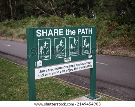 Fernleigh Track Belmont, NSW Australia - Share the Path signage for cyclists and pedestrians. Green wooden sign with text and pictures outlining safety tips for all users of the path.