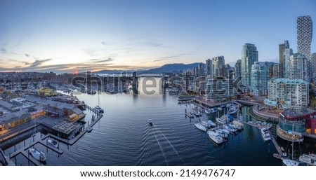 Panoramic Aerial View of False Creek with modern city skyline and mountains in background. Sunset Sky. Downtown Vancouver, British Columbia, Canada.