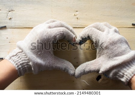 Hand in work gloves showing a sign of a heart. Love of a profession concept