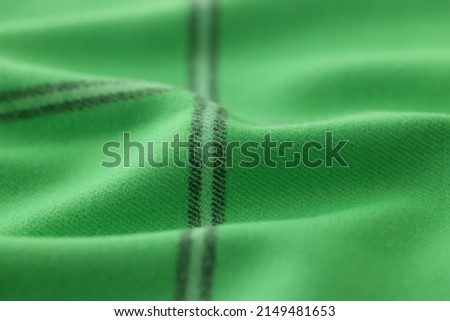 Warm green khaki knitted wool background with black stripes. Beautiful knitted wool textile with black vertical stripes.