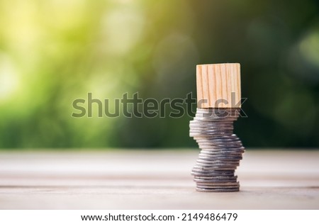 Coins stacked high on the table and Wooden blocks that can be put symbols high risk concept of financial business. planning savings money to buy a home, concept for property, mortgage, real estate.