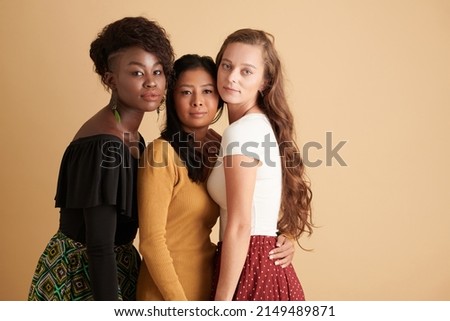 Group of unsmiling young female friends standing next to each other, hugging and looking at camera Royalty-Free Stock Photo #2149489871
