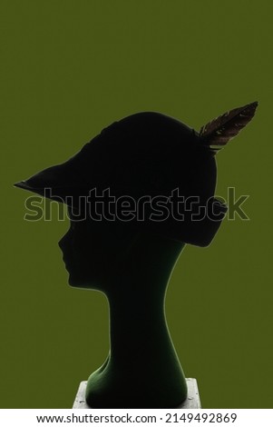 puppet head silhouette profile wearing alpin military hat with feather, green background, copy space