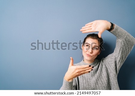 Young beautifu woman over isolated blue background thinking making frame with hands and fingers. Creativity and photography concept.