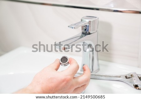 the repairman removes and cleans the Aerator from water stone and rust. special nozzle on the spout spout of the mixer from several strainers. Royalty-Free Stock Photo #2149500685
