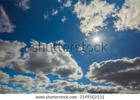 Beautiful view of sun with white clouds against blue sky.