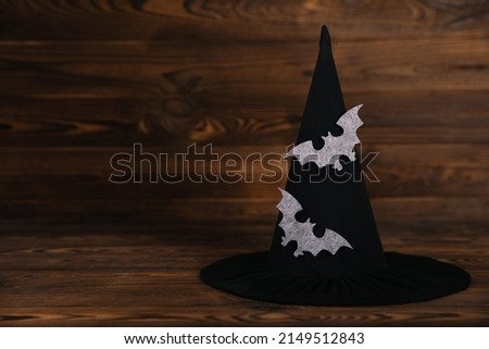 Witch hat with bats print on brown textured wooden background. Halloween holiday concept.Place for copy. Side view.