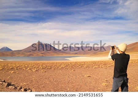 Visitor shooting photos of Miscanti lake with Mt. Cerro Miscanti in the backdrop, highland of Antofagasta region, northern Chile
