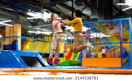 Pretty girl and her daughter kid jumping on colorful trampoline at playground park and smiling. Caucasian family happy during active entertaiments Royalty-Free Stock Photo #2149538781