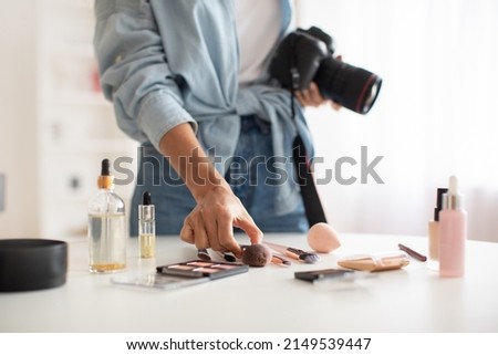 Professional Photography. Unrecognizable Female Photographer Holding Camera Taking Photos Of Makeup Products On Desk At Home. Cropped Shot, Selective Focus
