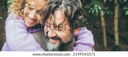 Close up portrait of joyful caucasian couple hugging an dloving with forest nature in background. Man and woman smiling and having fun together in outdoor leisure activity. Banner header image Royalty-Free Stock Photo #2149543571