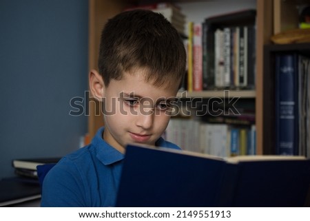 Young boy reading book at home library