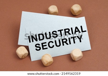 The concept of industrial safety. On a brown surface, wooden cubes and a business card with the inscription - Industrial Security
