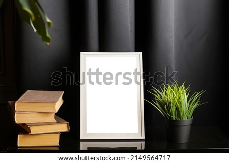 Stylish and modern workspace with white empty frame, books and houseplant on home or studio. High quality photo.