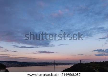 Beautiful European Lisbon, Portugal after sunset with evening sky and purple blue clouds. Evening cityscape with bridge, river and airplane  Royalty-Free Stock Photo #2149568057