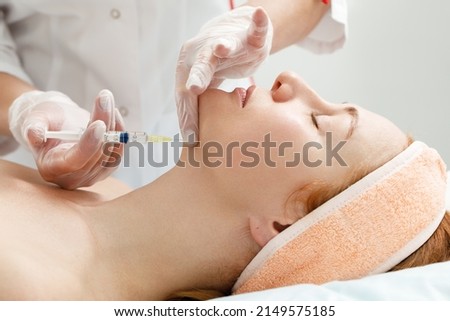 Cosmetologist performs the chin lift procedure by injecting beauty injections. Doctor injecting hyaluronic acid into the ching of a woman as a facial rejuvenation treatment. Royalty-Free Stock Photo #2149575185