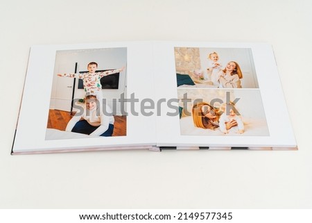 a Photobook of family at home on a white background. Photobook is gift. professional photographer and designer. printing of photos and journals in photo laboratory Royalty-Free Stock Photo #2149577345