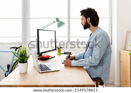 Professional young creative designer using digital graphic tablet and laptop computer with white blank screen from home office. Creative, design and business concept.