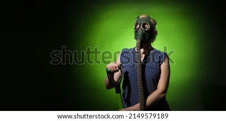 a woman in a gas mask leans on a shovel on a dark background with copy space, hard light