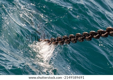 Anchor chain going dowm in the water with waves and splashes. Marine concept.